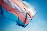 Transgender pride flag flying in front of blue sky